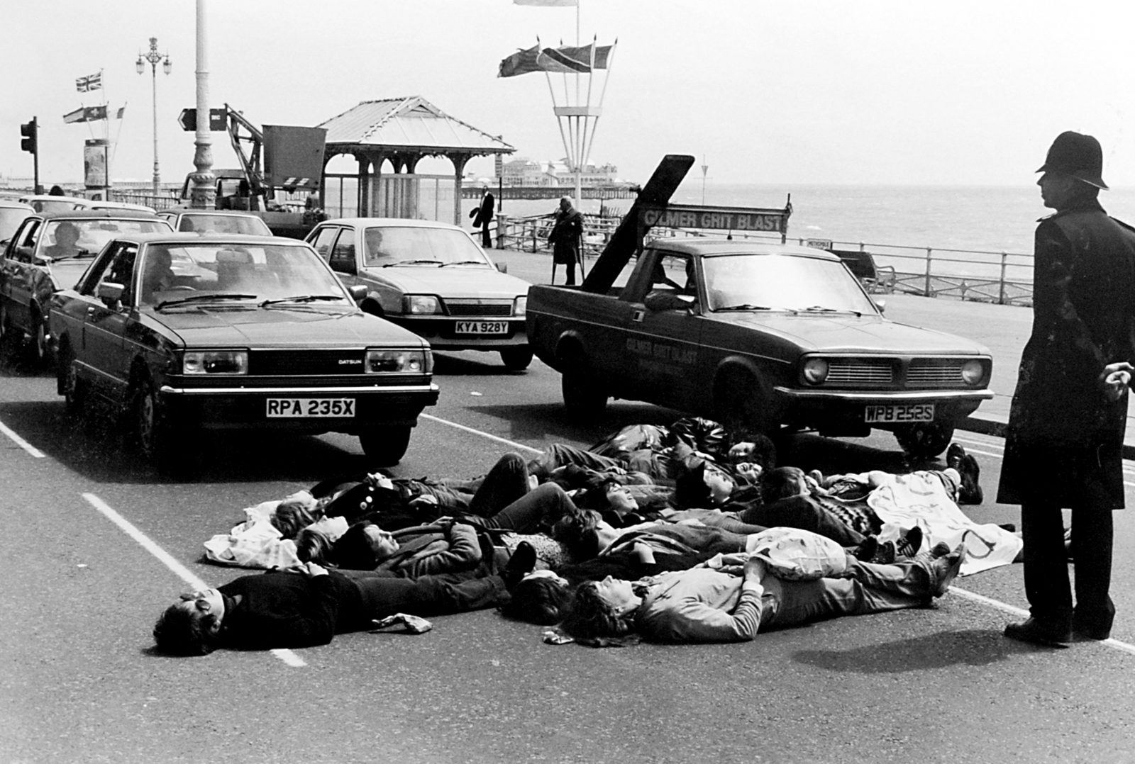 Black and white photograph of women lying on the road on Brighton seafront during a peace demo 1983