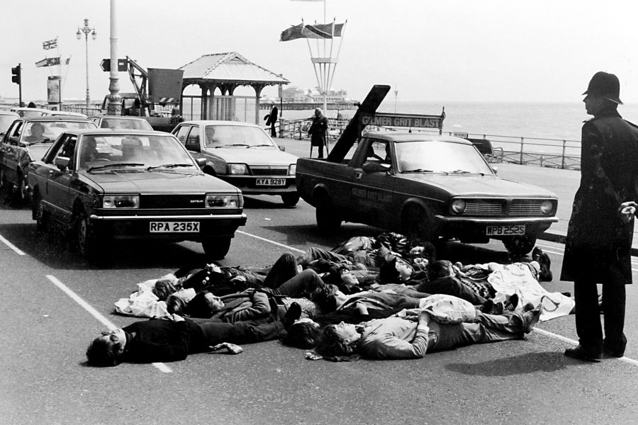 Black and white photograph of women lying on the road on Brighton seafront during a peace demo 1983