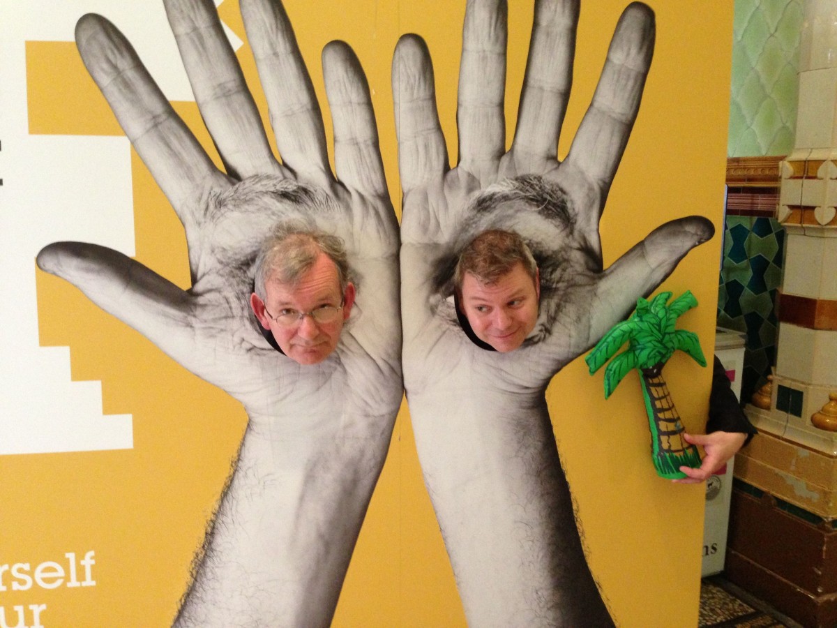 Martin Parr and Stephen Bull after Desert Island Pics, standing with their heads through Michael Rosen's hands in a Brighton Festival cut out.