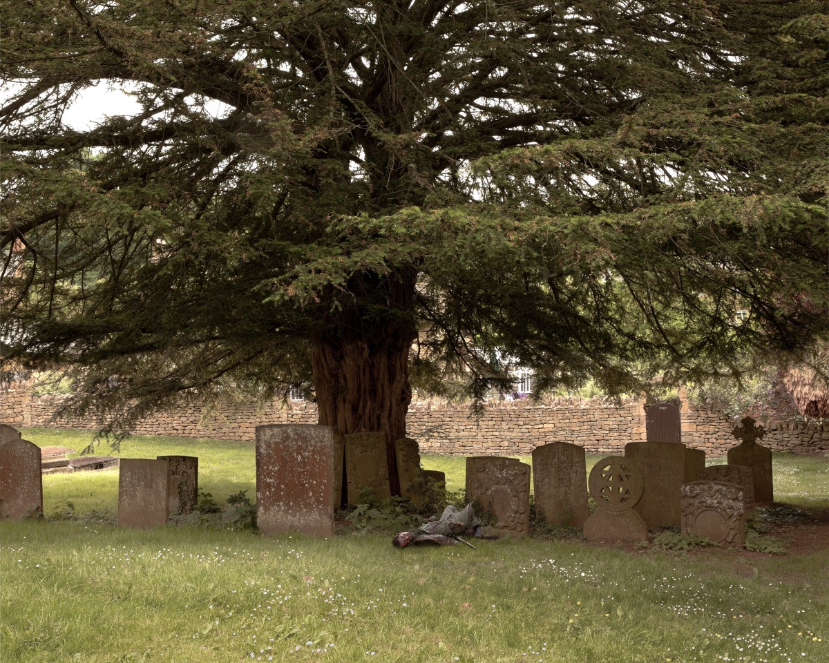 Young soldier lying among graves under large tree