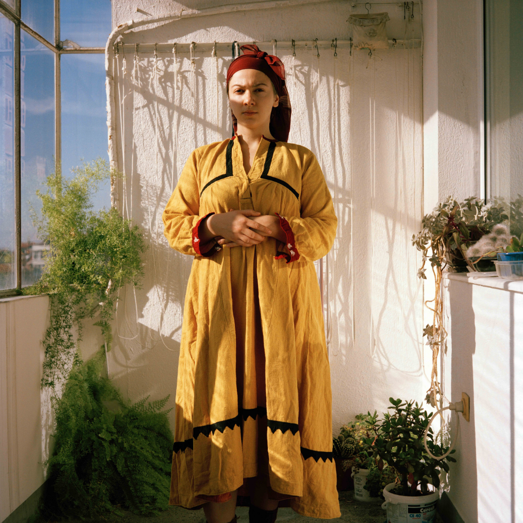 A self-portrait of the artist wearing her grandmother’s yellow dress. The dress is part of traditional Bulgarian folk dress which is usually worn with a cardigan, apron, headscarf and other accessories.